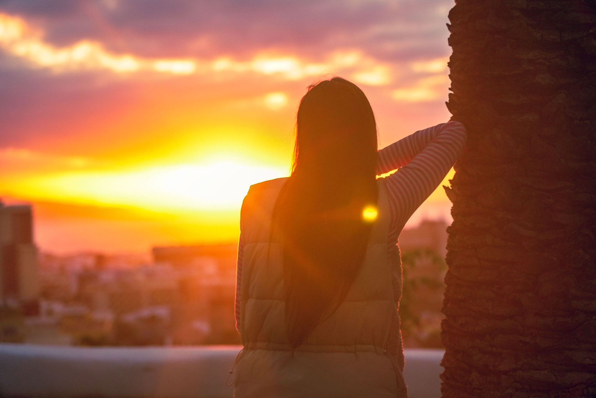 Woman looking out over the city at sunset