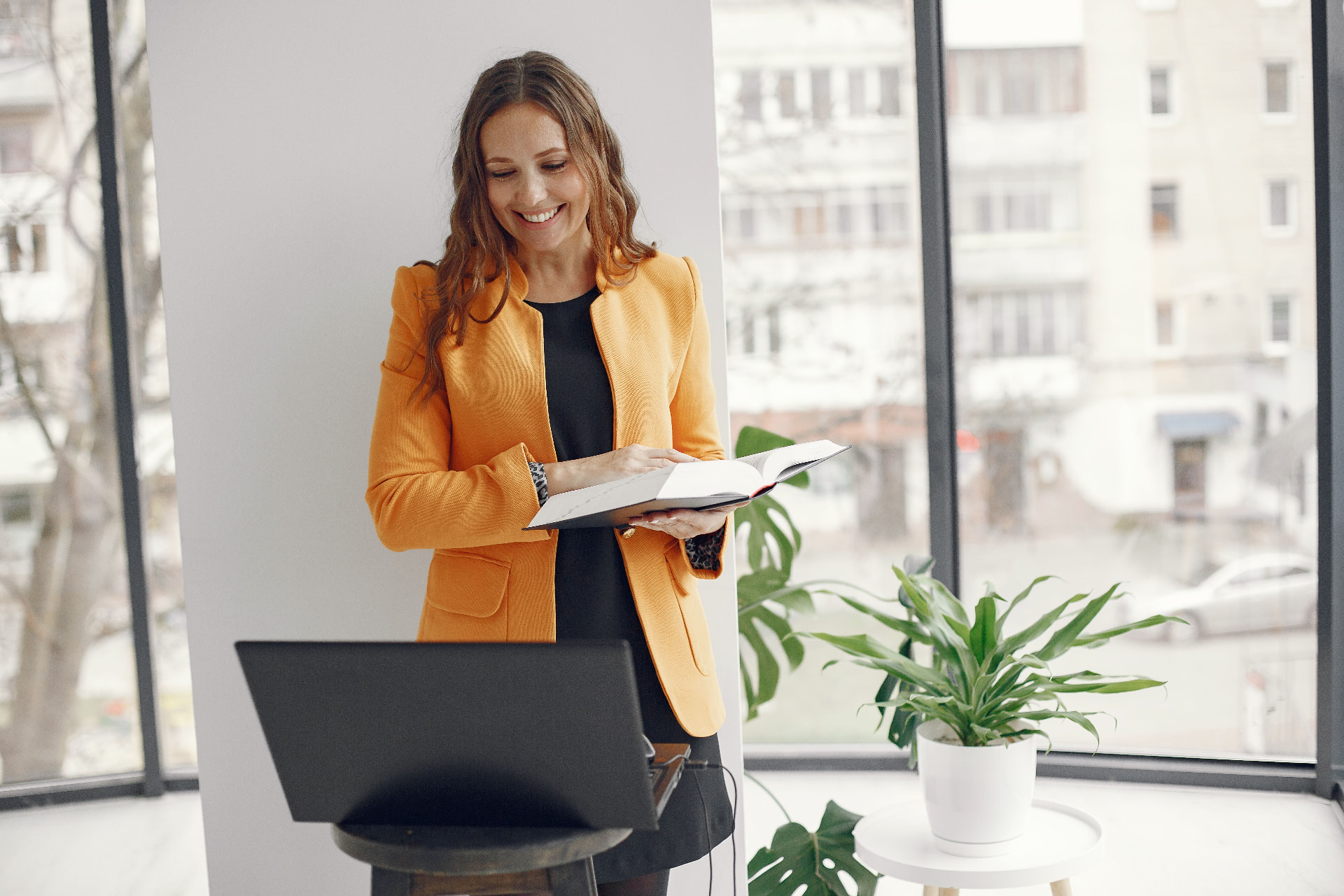Businesswoman smiling at her notebook by the office window